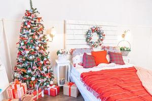 Classic interior room with Christmas tree and traditional white red decorations. Modern clean white classical style interior design apartment bedroom. Christmas eve at home. Minimalist home design. photo