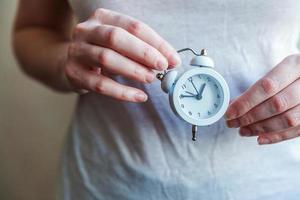 Female woman hands holding ringing twin bell vintage classic alarm clock. Rest hours time of life good morning night wake up awake concept. photo