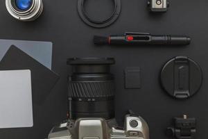 Photographer workplace with dslr camera system, camera cleaning kit, lens and camera accessory on dark black table background. Hobby travel photography concept. Flat lay top view copy space. photo