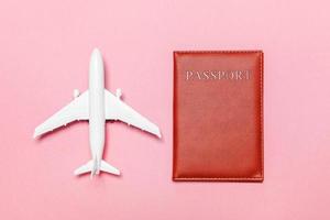 concepto de viaje de aventura de viaje plano simple mínimo con avión y pasaporte sobre fondo moderno de moda rosa pastel foto