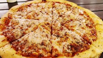 frische, duftende Pizza mit Käse, in Stücke geschnitten, liegt auf dem Esstisch.