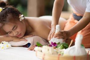 Massage spa relaxing treatment of office syndrome traditional thai massage style. Asian female massage traditional compress for hot massage back pain, arm pain and stress for woman tired from work. photo