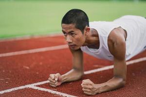 atletas deportistas corredores que visten ropa deportiva blanca para estirar y calentar antes de practicar en una pista de atletismo en un estadio. concepto de deporte de corredor. foto