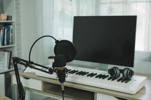 Home music studio condenser studio microphone, piano and white headphone for mixing production song. Home studio recording equipment. Music instrument concept.