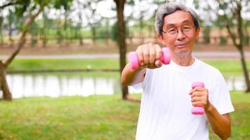 Happy asian man doing exercise by lifting dumbbells at the park. photo