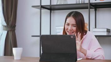 A young woman having video call with family on tablet computer at home. photo