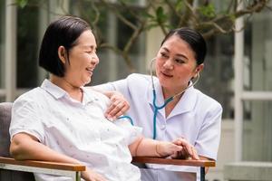 Asian nurse auscultating for female patient by using stethoscope at the hospital park photo