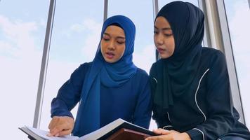 Two Muslim Asian women wearing traditional hijab are reciting prayers in the Quran. photo