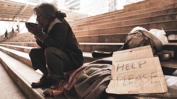 hombre sin hogar sentado en las escaleras y comiendo comida. foto