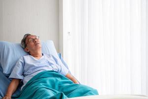 Asian patient man lying down on hospital  bed in the hospital room. photo