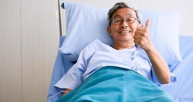 Male patient smiling and lying down on sickbed in hospital room. photo