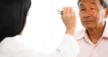 Female doctor checking male patient's eyes at hospital room. photo