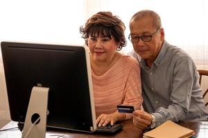 Asian couples doing financial transactions together by computer in the house. photo