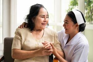 Beautiful nurse comforting female patient in the room. photo