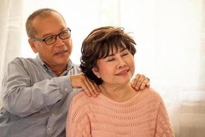 Happy asian husband massaging his wife shoulder in the house. photo