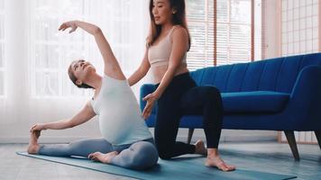 mujer embarazada haciendo ejercicio de pilates con entrenador personal en casa. foto