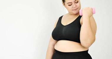 Chubby woman doing exercise by dumbbell in a room. photo