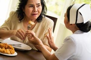 enfermera que prohíbe a una paciente adulta comer pollo frito en la habitación. foto