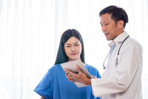 Asian doctor explaining works from tablet to medical assistants. photo