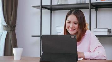 A young woman having video call with family on tablet computer at home. photo