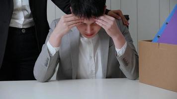 Young businessman is stressed because of being fired from his job. A colleague held his by the shoulder to encourage his. photo