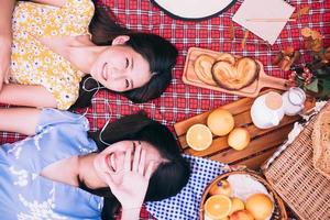 Two female friends enjoying picnic together in a park. photo