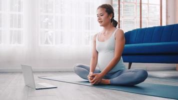 mujer embarazada asiática haciendo ejercicios de yoga en casa. foto