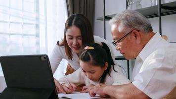 Grandfather and mother are teaching daughter homework while studying online at home. photo