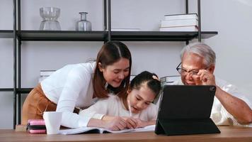Grandfather and mother are teaching daughter homework while studying online at home. photo