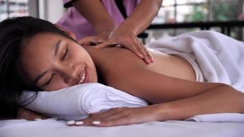 The massage therapist massaging on the back of young Asian woman with aroma essential oil skincare at spa salon. photo