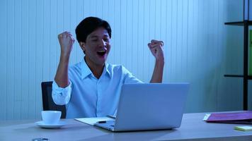 Office man looked at the laptop and he smiled and raised his hand, showing signs of joy and happiness, Excited young man, making yes gesture photo
