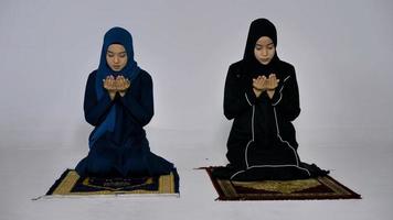 dos jóvenes musulmanas asiáticas con hiyab tradicional rezan para glorificar a alá y practican la fe islámica en la mezquita. foto