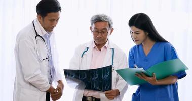 Doctor and medical assistants discussing about diagnosis result on x-ray film.