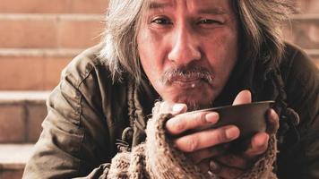 Homeless man sitting on stairs and eating food. photo