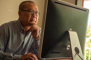 hombre de negocios asiático sentado y mirando la computadora en la sala de la oficina. foto