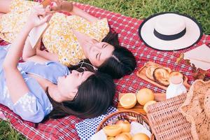 Two female friends enjoying picnic together in a park. photo