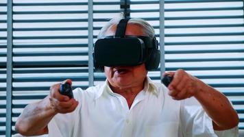 Asian senior man having fun playing video game with virtual reality glasses at home. photo