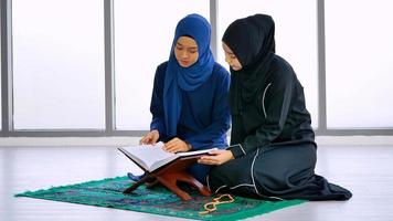 dos mujeres asiáticas musulmanas que usan hiyab tradicional están recitando oraciones en el corán. foto