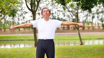 Asian man doing exercise by lifting dumbbells at the park. photo