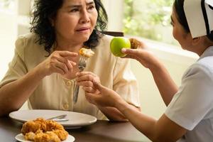 enfermera sugiriendo a una paciente adulta que coma manzana en lugar de pollo frito. foto