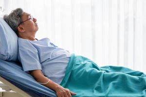 Asian patient man lying down on hospital bed in the hospital room. photo