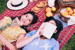 Two female friends enjoying picnic together in a park. photo