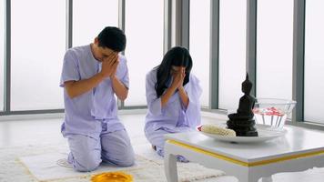pareja budista asiática rezando a la imagen de buda. foto