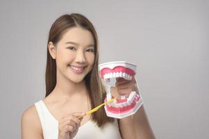 Young smiling woman holding toothbrush over white background studio, dental healthcare and Orthodontic concept. photo