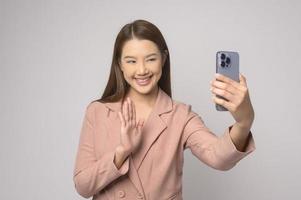 joven asiática usando un teléfono inteligente sobre fondo blanco, concepto de tecnología. foto