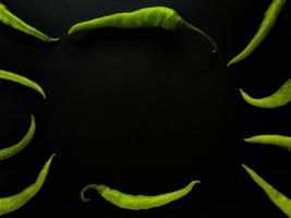 Natural green chilies on a dark background. Top view with food background, black stone table, copy space. photo