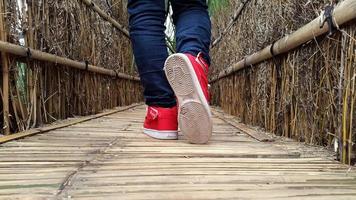 man's feet are walking on the bridge in red shoes and white soles photo