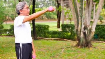 Asian man doing exercise by lifting dumbbells at the park. photo