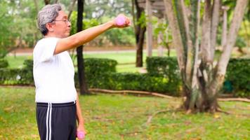 hombre asiático haciendo ejercicio levantando pesas en el parque. foto