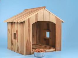 empty wooden dog's house with dog food bowl   Isolated on blue background. photo